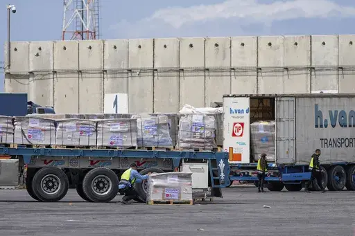 Trucks carrying humanitarian aid for the Gaza Strip pass through the inspection area at the Kerem Shalom Crossing in southern Israel, Thursday, March 14, 2024. (AP Photo/Ohad Zwigenberg)