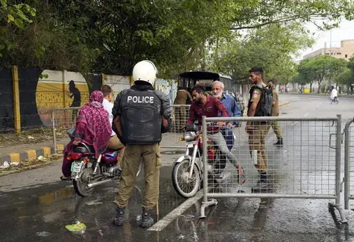 Pakistani security officials close a road outside the former Prime Minister Imran Khan's residence in Lahore, Pakistan, Thursday, May 18, 2023. Pakistani police kept up their siege around the home of Khan as a 24-hour deadline given to the former premier to hand over suspects allegedly sheltered inside was about to expire on Thursday. (AP Photo/K.M. Chaudary)