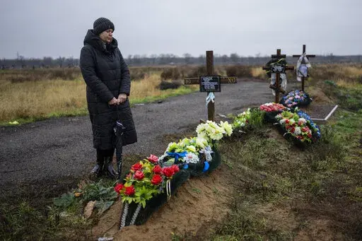 Svetlana Shornik stands next to the grave of her 53-year-old ex-husband, Oleh Shornik, on the outskirts Kherson, Ukraine, on Sunday, Nov. 20, 2022. Oleh Shornik was among 20 civilian volunteers of Ukraine’s Territorial Defense Forces killed by Russian troops in March in the southern city before it fell to Moscow. Russia held it for eight months before retreating in November. (AP Photo/Bernat Armangue)