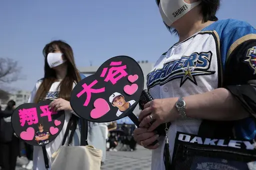 Fans of Japan's Shohei Ohtani cheer prior to the Pool B game between Japan and China at the World Baseball Classic (WBC) at the Tokyo Dome Thursday, March 9, 2023, in Tokyo. The paper fans read in Japanese "Ohtani, " right, and "Shohei." Japanese baseball player Shohei Ohtani is arguably the game's best player. But he's more than just a baseball player. He's an antidote for many in his native country. (AP Photo/Eugene Hoshiko)