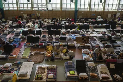 People who fled the war in Ukraine rest inside an indoor sports stadium being used as a refugee center, in the village of Medyka, a border crossing between Poland and Ukraine, on Tuesday, March 15, 2022.(AP Photo/Petros Giannakouris)