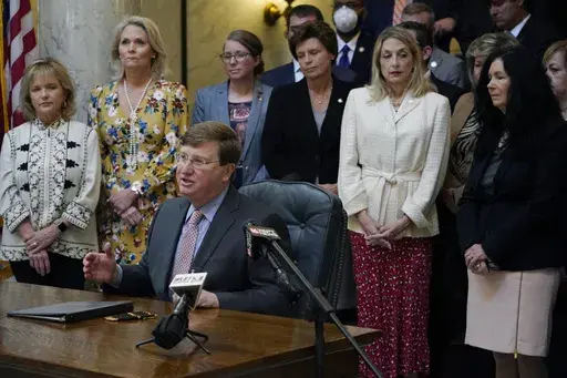 Mississippi Republican Gov. Tate Reeves is surrounded by legislative supporters after signing a bill to ban transgender athletes from competing on girls' or women's sports teams on March 11, 2021, at the state Capitol in Jackson, Miss. On Monday, April 29, 2024, Mississippi House and Senate negotiators quietly killed two bills that would have further restricted recognition of transgender people by limiting which bathrooms they could use in public buildings and by specifying that "there are only 