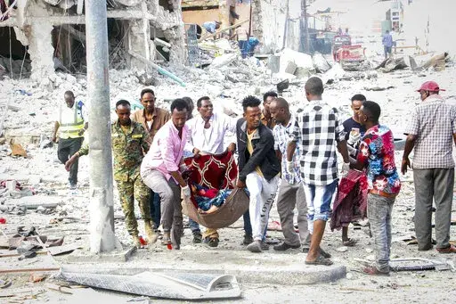 Rescuers remove a seriously-injured body from the scene of a double car-bomb attack in the capital Mogadishu, Somalia Saturday, Oct. 29, 2022. Two car bombs exploded Saturday at a busy junction in Somalia's capital near key government offices, leaving "scores of civilian casualties," police told state media. (AP Photo/Farah Abdi Warsameh)