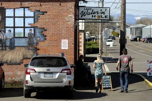 Customers walk toward the Last Waterin' Hole restaurant in North Plains, Ore., on March 17, 2023. In an attempt to attract semiconductor companies to Oregon, the state Legislature on Thursday, April 6, 2023, authorized the governor to expand urban growth boundaries to provide land for chip makers to build factories and provides over $200 million in grants to chipmakers. (AP Photo/Andrew Selsky, File)