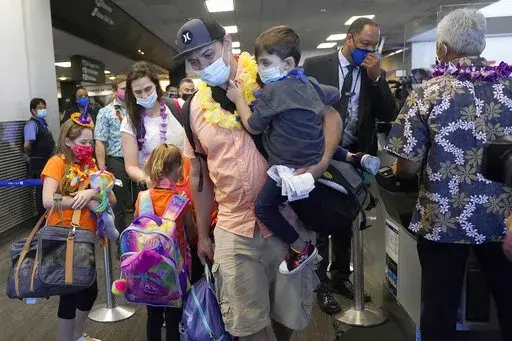 In this Oct. 15, 2020 file photo, Hawaii resident Ryan Sidlow carries his son Maxwell as their family boards a United Airlines flight to Hawaii at San Francisco International Airport in San Francisco. The Transportation Department is rolling out a “dashboard” to let travelers see at a glance which airlines help families with young children sit together at no extra cost. The announcement Monday, March 6, 2023 comes as the department works on regulations to prevent families from being separate