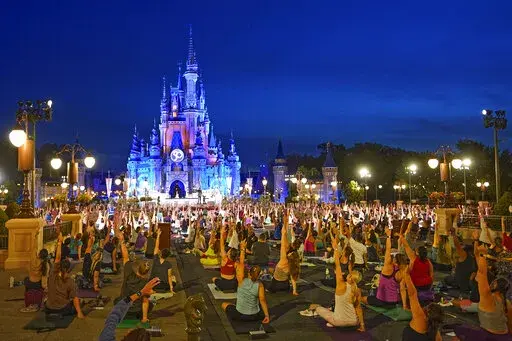 Nearly 2,000 cast members practice sunrise yoga celebrating International Yoga Day in front of Cinderella Castle at the Magic Kingdom Park at Walt Disney World Tuesday, June 21, 2022, in Lake Buena Vista, Fla. (AP Photo/John Raoux)