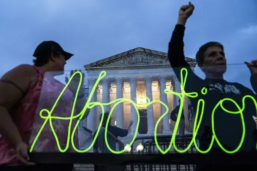 Activists mark the first anniversary of the Supreme Court's decision in Dobbs v. Jackson Women's Health Organization, by displaying neon signage in support of abortion access in front of the Supreme Court on June 23, 2023, in Washington. A report finds the total number of monthly abortions in the U.S. increased after state bans started kicking in in 2022. (AP Photo/Nathan Howard, File)