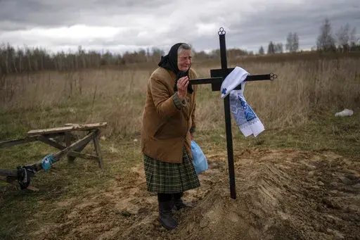 Nadiya Trubchaninova, 70, cries while holding the cross of her son Vadym, 48, who was killed by Russian soldiers last March 30 in Bucha, during his funeral in the cemetery of Mykulychi, on the outskirts of Kyiv, Ukraine, Saturday, April 16, 2022. After nine days since the discovery of Vadym's corpse, finally Nadiya could have a proper funeral for him. This is not where Nadiya Trubchaninova thought she would find herself at 70 years of age, hitchhiking daily from her village to the shattered town