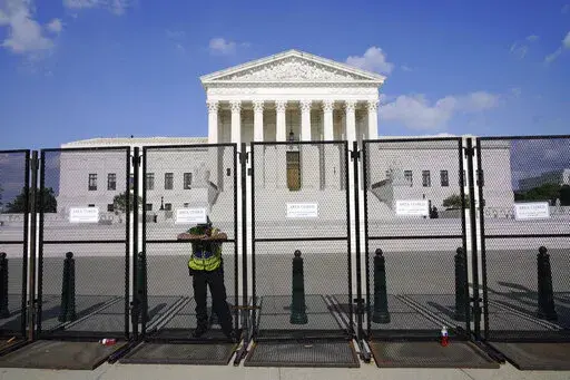 An officer rests on a fence outside the Supreme Court in Washington, Friday, June 24, 2022. The Supreme Court has ended constitutional protections for abortion that had been in place nearly 50 years, a decision by its conservative majority to overturn the court's landmark abortion cases. (AP Photo/Jacquelyn Martin)