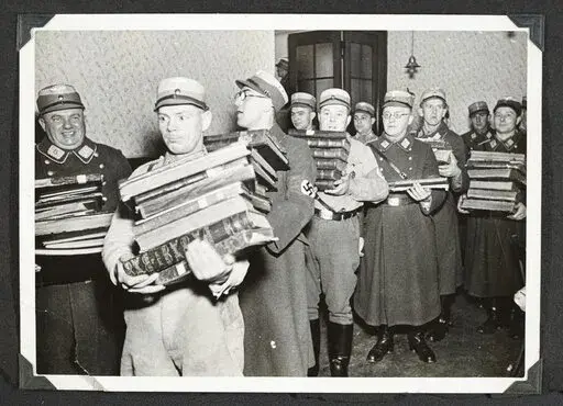 This photo released by Yad Vashem, World Holocaust Remembrance Center, shows German Nazis carry Jewish books, presumably for burning, during Kristallnacht intake most likely in the town of Fuerth, Germany on Nov. 10, 1938. The photos were taken by Nazi photographers during the pogrom in the city of Nuremberg and the nearby town of Fuerth. They wound up in the possession of a Jewish American serviceman who served in Germany during World War II. His descendants,donated the album to Yad Vashem. (Ya