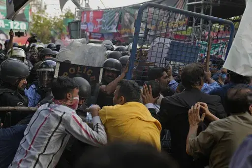 Supporters of former Prime Minister Imran Khan's party scuffle with riot police officers outside Khan's residence, in Lahore, Pakistan, Tuesday, March 14, 2023. Pakistani police scuffled with supporters of former Prime Minister Imran Khan as officers arrived outside his home to arrest him for failing to appear in court on graft charges, police and officials said. (AP Photo/K.M. Chaudary)