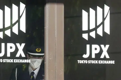 A security guard stands guard at the entrance of the Tokyo Stock Exchange building Wednesday, Nov. 2, 2022, in Tokyo. Asian shares were mostly higher Wednesday ahead of a decision by the U.S. Federal Reserve on an interest rate increase to curb inflation. (AP Photo/Eugene Hoshiko)