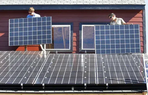 Workers install two of 105 solar panels on the roof of a barn Thursday, Aug. 27, 2009, north of Hesperus, Colo. The Inflation Reduction Act includes tax credits and rebates for homeowners who make energy-saving updates to their homes. Tax credits are available now for updates like new windows, doors, air conditioners, insulation and solar panels, while larger rebates for energy-saving and electrification updates are expected to become available later this year or early next year. (AP Photo/Jerry