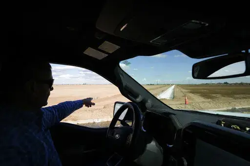 Tom Brundy points to a newly built irrigation canal on one of the fields at his farm Tuesday, Feb. 28, 2023, near Calexico, Calif. Brundy, an alfalfa grower in California's Imperial Valley, thinks farmers reliant on the shrinking Colorado River can do more to save water and use it more efficiently. But one practice that's off-limits for Brundy is fallowing — leaving fields unplanted to spare the water that would otherwise irrigate crops. (AP Photo/Gregory Bull)