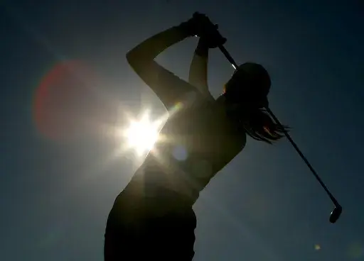 A golfer is silhouetted against the sun while teeing off on the third hole during the first round of the Women's British Open golf tournament at Royal Lytham and St Annes golf course in Lytham, north west England Thursday, Aug. 3, 2006. Kerry Bowie's daughters have dreams. Big ones. “There are some things people miss out on by not doing it,” Bowie says. “To be that young lady who plays golf, it changes things.” (AP Photo/Matt Dunham, File)