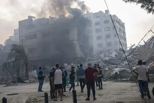 Journalists observe as Palestinians inspect the rubble of a building after it was struck by an Israeli airstrike, in Gaza City, Sunday, Oct. 8, 2023. Journalists reporting in Gaza need to worry about basic survival for themselves and their families in addition to getting out the story of a besieged population. (AP Photo/Fatima Shbair, File)