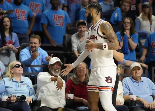 Auburn forward Johni Broome, front right, reaches out and apologizes to Academy Award-winning actor and Mississippi fan Morgan Freeman, second from front left, after falling into him while going after the ball during the second half of an NCAA college basketball game against Mississippi, Saturday, Feb. 3, 2024, in Oxford, Miss. (AP Photo/Rogelio V. Solis)