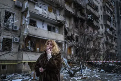 Natali Sevriukova reacts next to her house following a rocket attack the city of Kyiv, Ukraine, on Feb. 25, 2022. The yearlong war in Ukraine has left tens of thousands of dead and wounded on both sides, disrupted energy and food supplies, and reduced whole cities to ruins. (AP Photo/Emilio Morenatti, File)