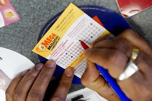 A customer fills out a Mega Millions lottery ticket at a convenience store in Northbrook, Ill., on Jan. 6, 2021. Lottery players will have a chance to ring in the New Year with a $640 million bonus in their bank account as a drawing is held Friday, Dec. 30, 2022 in the Mega Million game. (AP Photo/Nam Y. Huh, File)