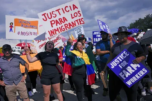People carry signs that read in Spanish, "Justice for Immigrants" and "We are humans" as hundreds gather to protest peacefully against Florida Senate bill 1718, which imposes restrictions on undocumented immigrants, Thursday, June 1, 2023, in Immokalee, Fla., an area known for its tomato-growing. Across Florida Thursday, workers didn't show up at construction sites, and tomato fields, while scores of restaurants and small businesses never opened their doors to protest the new state law. (AP Phot