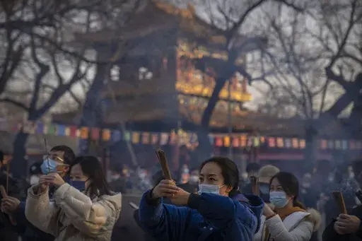 Visitors burn incense as they pray on the first day of the Lunar New Year holiday at the Lama Temple in Beijing on Jan. 22, 2023. (AP Photo/Mark Schiefelbein, File)