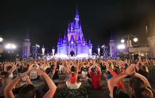On the morning of the summer solstice, Walt Disney World cast members stretch at Cinderella Castle in the Magic Kingdom, in Lake Buena Vista, Fla., in a pre-dawn gathering before the park opened Wednesday, June 21, 2023, for their annual team yoga session to commemorate International Yoga Day. An estimated 2,000 employees participated in Wednesday's rain-shortened event, now in its 7th year at Disney World. The International Day of Yoga occurs worldwide each year on the summer solstice and was e