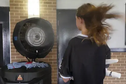 Samantha Martns of Chicago, stands in front of a cooling station on the concourse of Guaranteed Rate Field before a baseball game between the Chicago White Sox and the Seattle Mariners Wednesday, Aug. 23, 2023, in Chicago. (AP Photo/Charles Rex Arbogast)