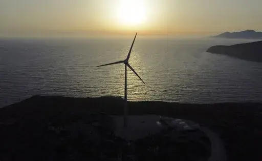 The sun sets behind a wind turbine on the Aegean Sea island of Tilos, southeastern Greece, Monday, May 9, 2022. When deciding where to test green tech, Greek policymakers picked the remotest point on the map, tiny Tilos. Providing electricity and basic services, and even access by ferry is all a challenge for this island of just 500 year-round inhabitants. It's latest mission: Dealing with plastic. (AP Photo/Thanassis Stavrakis)