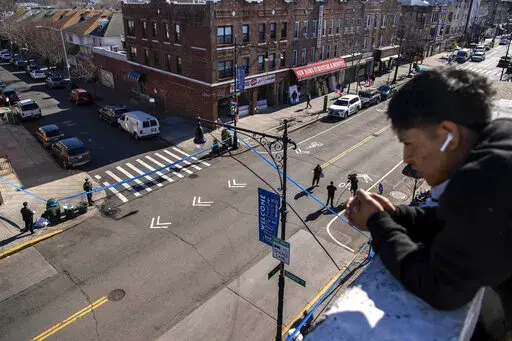 FILE —-Erafin Yaz, 25, looks from his roof at the caution tape covering the corner of Bay Ridge Avenue and 5th Avenue where pedestrians were struck Monday, Feb. 13, 2023, in the Brooklyn borough of New York. Delivery worker YiJie Ye was struck and killed by a U-Haul truck during a miles-long rampage, that barreled into bicyclists, moped riders, a police car and one pedestrian. (AP Photo/Brittainy Newman)